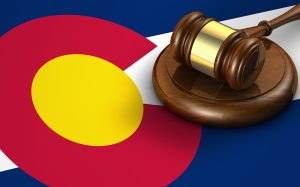 Gavel resting on a wooden block against a bold red, yellow, blue flag background, symbolizing law and justice.